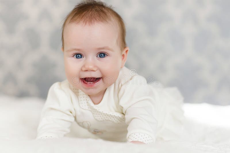 Retrato de um bebê de rastejamento na cama em sua sala foto de stock Retrato de um bebê de rastejamento na cama em sua sala foto de stock