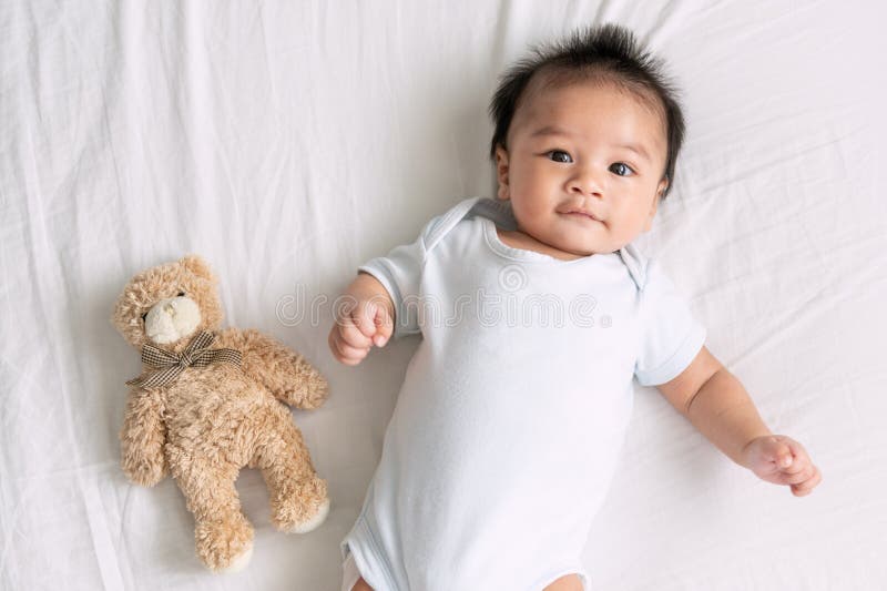 Retrato de um bebê de rastejamento na cama em sua sala, bebê adorável no quarto ensolarado branco, criança recém-nascida que rela fotografia de stock royalty free Retrato de um bebê de rastejamento na cama em sua sala, bebê adorável no quarto ensolarado branco, criança recém-nascida que rela fotografia de stock royalty free