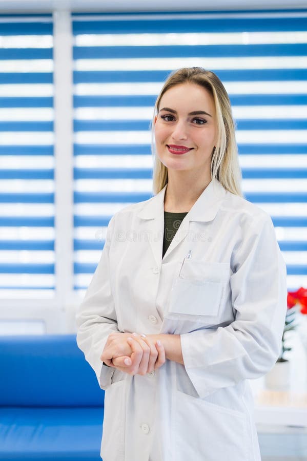 Retrato de um doutor fêmea novo que veste um revestimento branco que levanta no escritório do hospital foto de stock Retrato de um doutor fêmea novo que veste um revestimento branco que levanta no escritório do hospital foto de stock