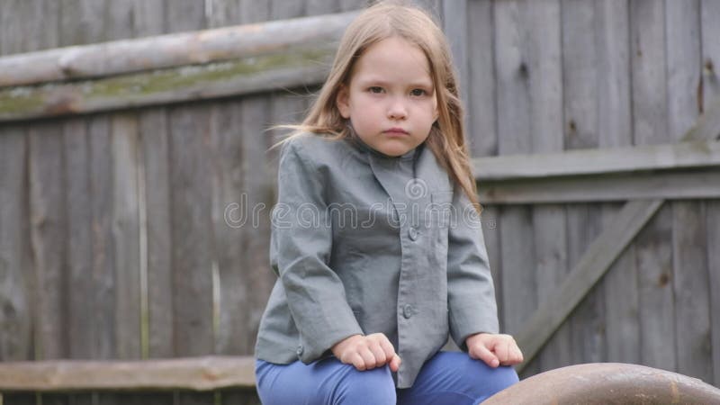 Retrato de um fazendeiro sério pequeno bonito da menina que senta-se na jarda