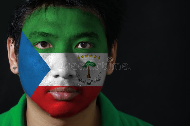 Retrato de um homem com a bandeira da Guiné Equatorial pintada em sua cara no fundo preto foto de stock royalty free Retrato de um homem com a bandeira da Guiné Equatorial pintada em sua cara no fundo preto foto de stock royalty free