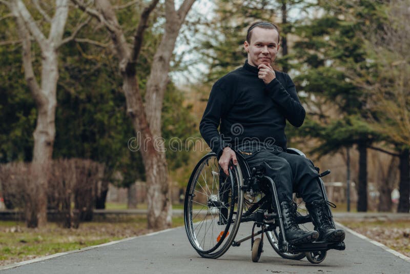 Retrato de um homem feliz em uma cadeira de rodas em um parque fotos de stock Retrato de um homem feliz em uma cadeira de rodas em um parque fotos de stock
