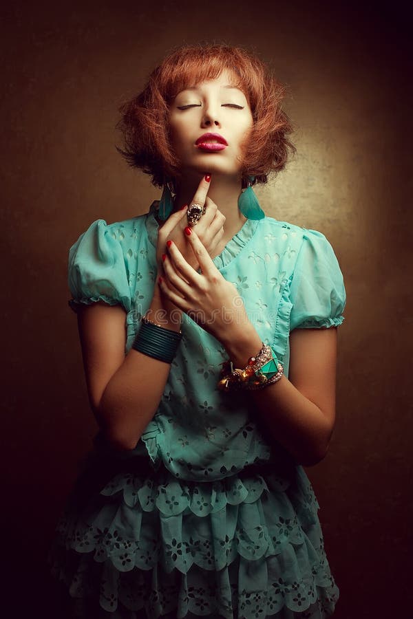 Portrait of a young doll-like girl with fashionable accessories earrings, armlets, ring posing over golden background. Perfect hair, make-up and manicure. Japanese anime style. Studio shot. Portrait of a young doll-like girl with fashionable accessories earrings, armlets, ring posing over golden background. Perfect hair, make-up and manicure. Japanese anime style. Studio shot