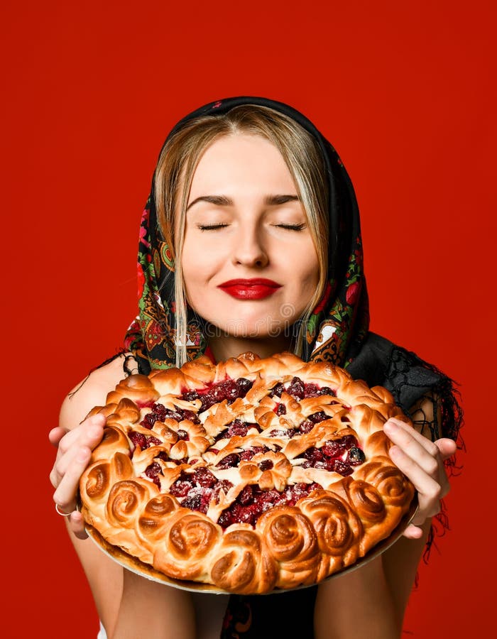 Retrato de um louro bonito novo no lenço que guarda uma torta caseiro deliciosa da baga imagens de stock Retrato de um louro bonito novo no lenço que guarda uma torta caseiro deliciosa da baga imagens de stock