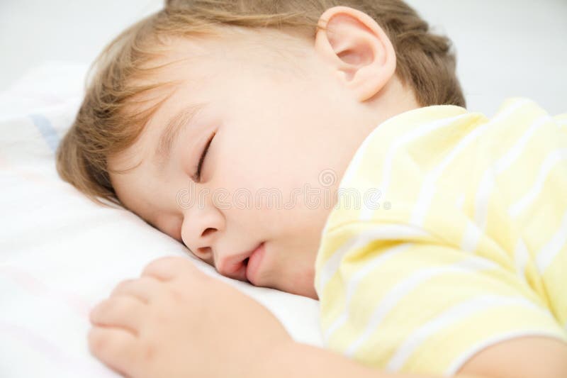O rapaz pequeno bonito está dormindo fotografia de stock O rapaz pequeno bonito está dormindo fotografia de stock
