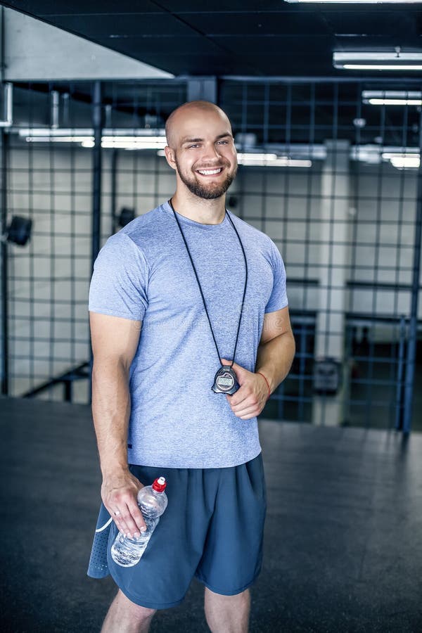 Retrato de um treinador de esportes de sorriso com uma cabe?a calva l olha a c?mera com cron?metro ? disposi??o o exerc?cio era b fotos de stock royalty free Retrato de um treinador de esportes de sorriso com uma cabe?a calva l olha a c?mera com cron?metro ? disposi??o o exerc?cio era b fotos de stock royalty free