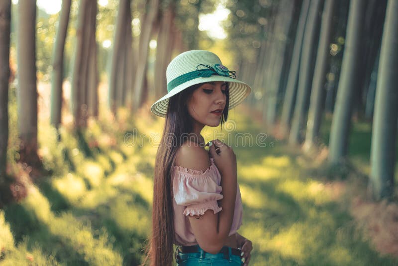 Retrato de uma blusa branca vestindo do rosa do chapéu do sol da menina latino-americano moreno consideravelmente de cabelos comp fotos de stock Retrato de uma blusa branca vestindo do rosa do chapéu do sol da menina latino-americano moreno consideravelmente de cabelos comp fotos de stock
