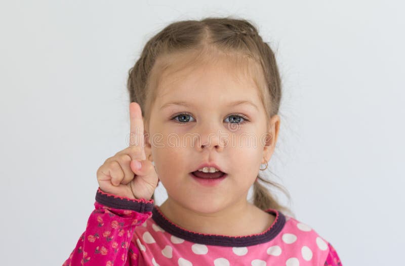 Retrato de uma criança caucasiana de três anos segurando o dedo para mostrar o número um ou dizendo importância olhando para a câm