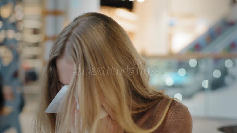 Retrato de uma jovem caucasiana com rinite pingar doença do vírus nasal espirra toalhetes com guardanapo de papel no shopping
