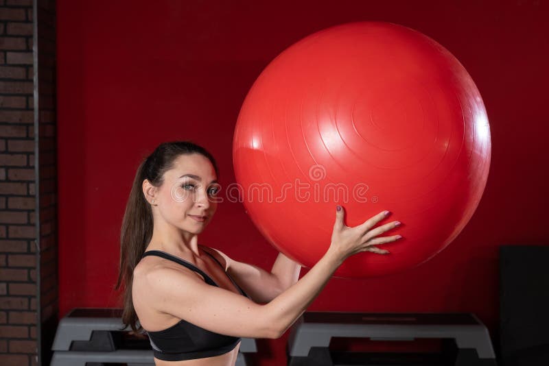 Retrato de uma jovem com um exercício de bola suíça e sorrindo para a câmera Imagem do modelo de adequação feminina ao vivo fotografia de stock Retrato de uma jovem com um exercício de bola suíça e sorrindo para a câmera Imagem do modelo de adequação feminina ao vivo fotografia de stock