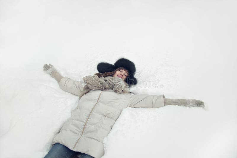 Retrato de uma jovem mulher bonita que estabelece em uma figura do anjo da neve fotos de stock royalty free Retrato de uma jovem mulher bonita que estabelece em uma figura do anjo da neve fotos de stock royalty free