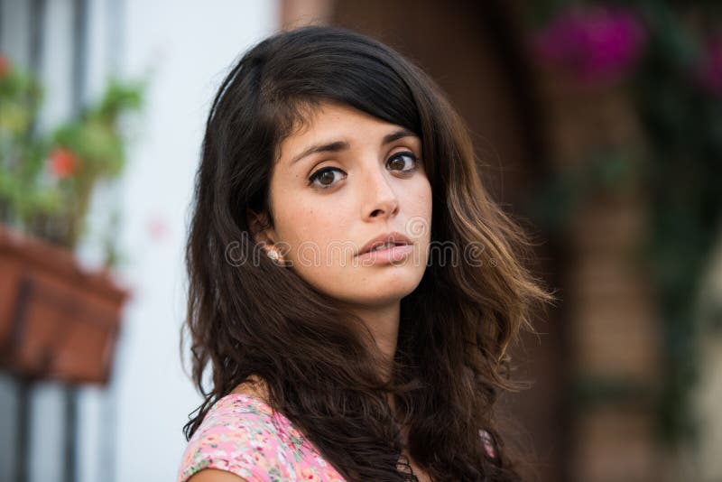 Retrato de uma jovem mulher em uma jarda espanhola tipical que olha na câmera imagem de stock royalty free Retrato de uma jovem mulher em uma jarda espanhola tipical que olha na câmera imagem de stock royalty free