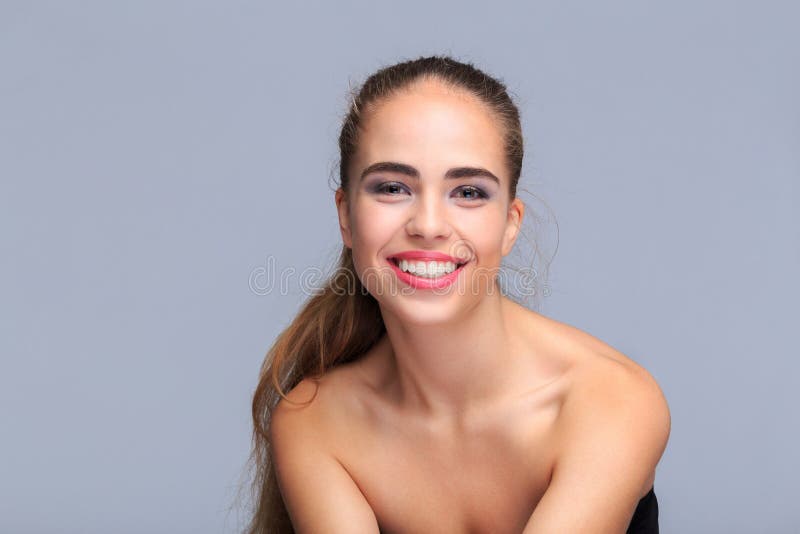Retrato de uma jovem mulher em uma luz - fundo cinzento, sorrindo, cosméticos imagens de stock Retrato de uma jovem mulher em uma luz - fundo cinzento, sorrindo, cosméticos imagens de stock