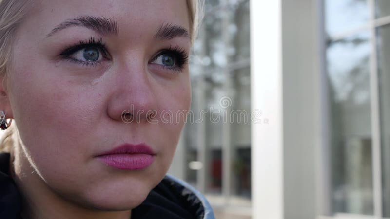 Retrato de uma loura choradora 4k. lágrimas enrolam o rosto de uma jovem. uma mulher triste limpa seus olhos cheios de