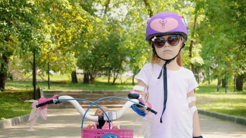 Retrato de uma menina bonito pequena em um capacete roxo da bicicleta