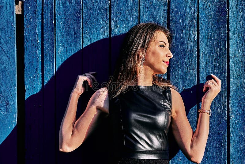 Retrato de uma morena magro nova da mulher em um vestido preto perto de uma cerca de madeira Noite ensolarada do ver?o foto de stock Retrato de uma morena magro nova da mulher em um vestido preto perto de uma cerca de madeira Noite ensolarada do ver?o foto de stock