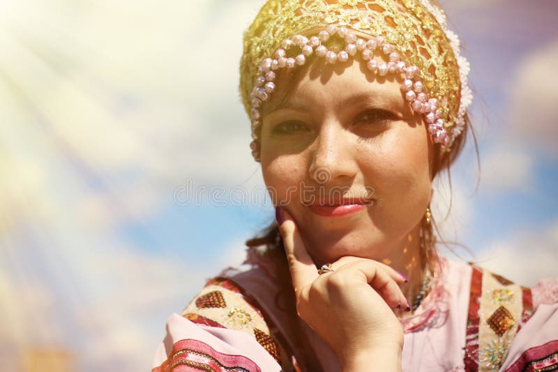 Retrato de uma moça no traje popular do russo no fundo do céu fotografia de stock royalty free Retrato de uma moça no traje popular do russo no fundo do céu fotografia de stock royalty free