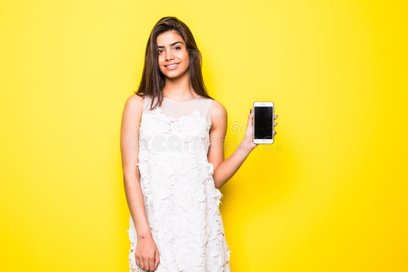 Retrato de uma mulher alegre que mostra a tela vazia do smartphone sobre o fundo amarelo fotos de stock Retrato de uma mulher alegre que mostra a tela vazia do smartphone sobre o fundo amarelo fotos de stock