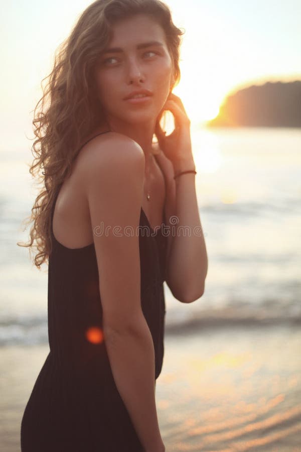 Retrato de uma mulher bonita nova com cabelo encaracolado longo no beira-mar foto de stock royalty free Retrato de uma mulher bonita nova com cabelo encaracolado longo no beira-mar foto de stock royalty free