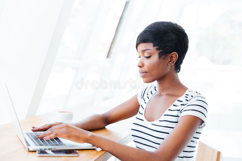 Retrato de uma mulher de negócios africana de sorriso ocasional que usa o laptop foto de stock Retrato de uma mulher de negócios africana de sorriso ocasional que usa o laptop foto de stock