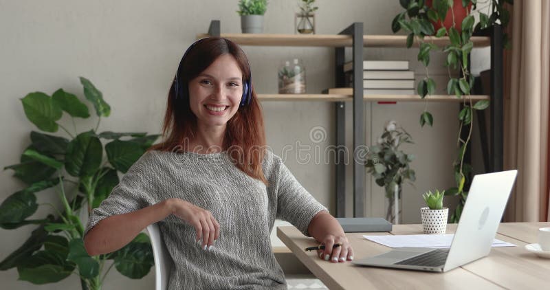 Retrato de uma mulher sorridente de cabelos vermelhos de 30 anos em fones de ouvido