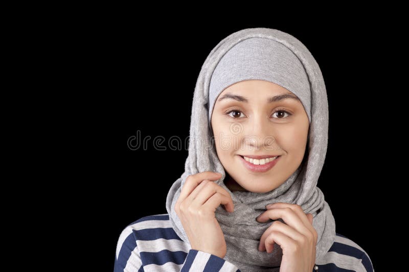 Retrato de un aspecto del este sonriente de la chica joven, con su cabeza cubierta en un Musulmán-estilo en un fondo negro imágenes de archivo libres de regalías Retrato de un aspecto del este sonriente de la chica joven, con su cabeza cubierta en un Musulmán-estilo en un fondo negro imágenes de archivo libres de regalías