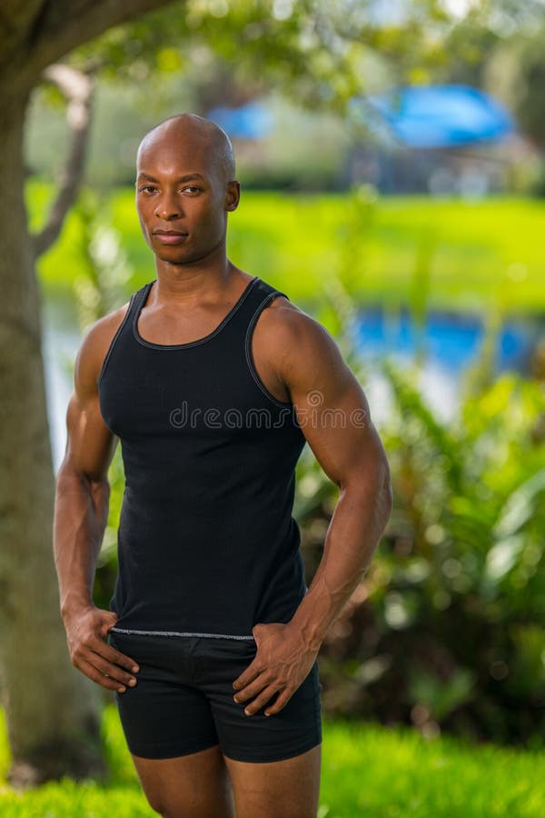 Retrato de un chico duro en una camisa de las camisetas sin mangas que presenta al aire libre foto de archivo libre de regalías