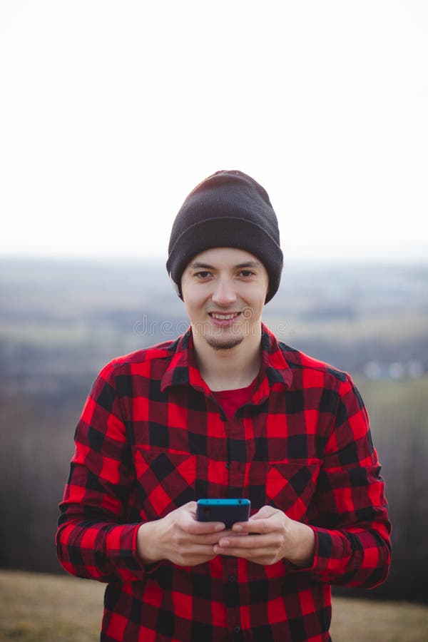 Retrato De Un Hombre De 23 Años De Edad Con Una Camisa Negra Y Roja a Cuadros Se Comunica Con Su Audiencia En Medios Sociales Imagen de archivo - Imagen de