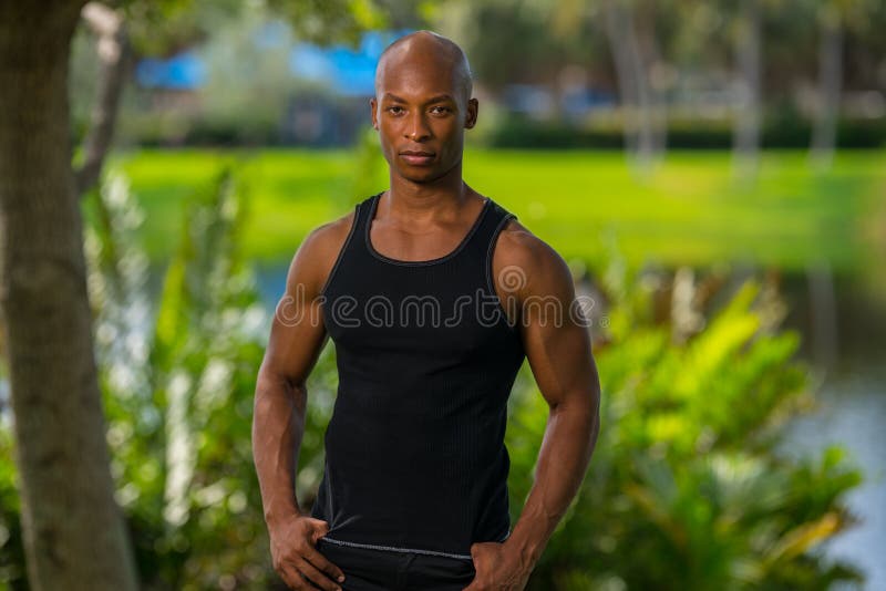 Retrato de un hombre afroamericano que presenta al aire libre en una camisa de las camisetas sin mangas Lit con del flash de la cámara