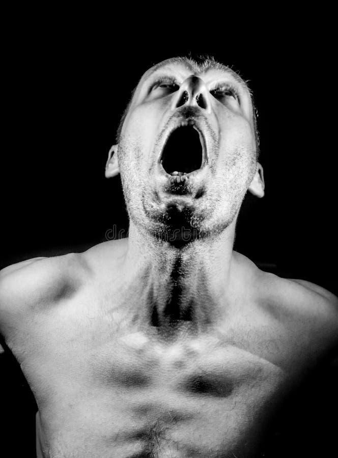 Retrato de un hombre caucásico adulto gritando en una oscuridad. gritando fuerte dolor y miedo concepto. negro y blanco fotografía de archivo
