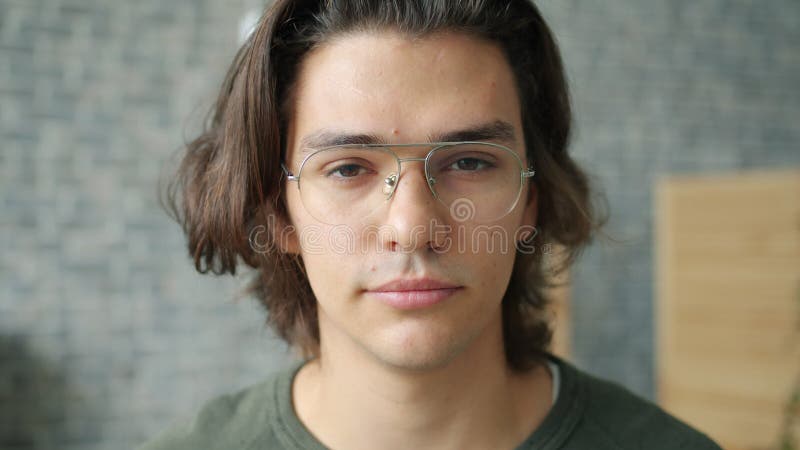 Retrato de un hombre guapo que usa gafas mirando la cámara solo en casa