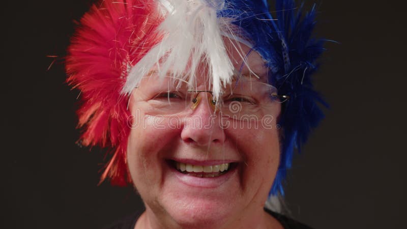 Retrato de un hombre sonriente en una peluca de colores que se cierra sobre un fondo gris. la mujer mira a la cámara y sonríe