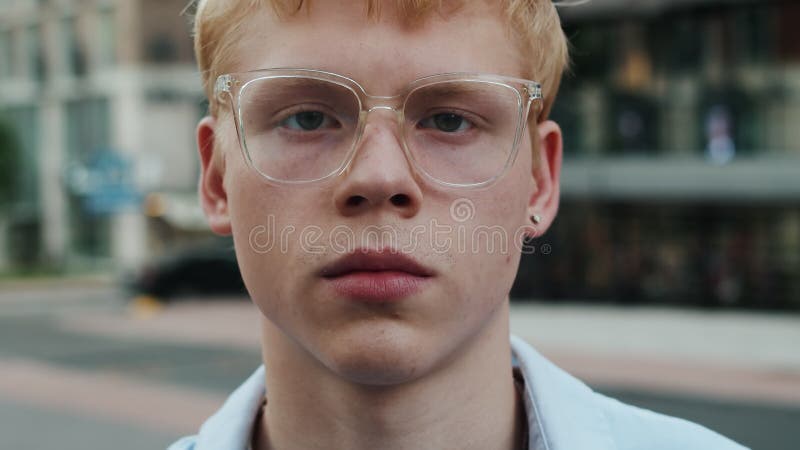 Retrato de un joven y apuesto hombre caucásico con gafas que levanta la cabeza mirando la cámara con una cara segura de sí misma almacen de metraje de vídeo