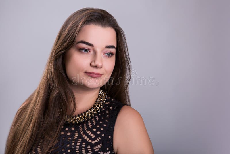 Retrato de un modelo femenino del tamaño extra grande que presenta en vestido negro sobre fondo gris imagen de archivo Retrato de un modelo femenino del tamaño extra grande que presenta en vestido negro sobre fondo gris imagen de archivo