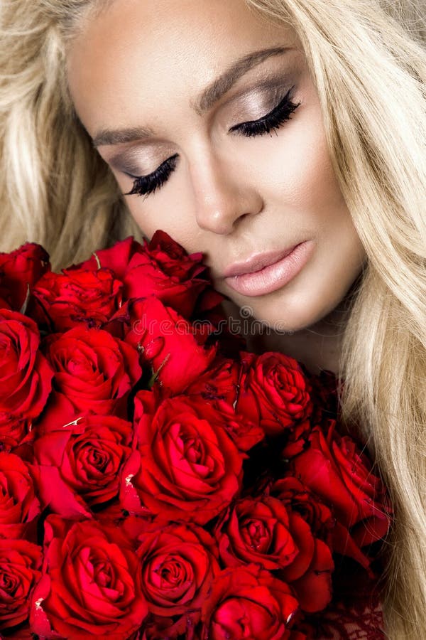Retrato de un modelo femenino rubio hermoso con el pelo largo, hermoso Modelo en la lencería sexy, sosteniendo rosas rojas