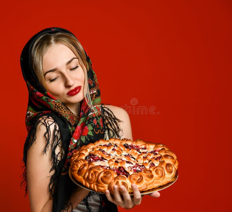 Retrato de un rubio hermoso joven en el pañuelo que sostiene una empanada hecha en casa deliciosa de la cereza fotografía de archivo libre de regalías Retrato de un rubio hermoso joven en el pañuelo que sostiene una empanada hecha en casa deliciosa de la cereza fotografía de archivo libre de regalías