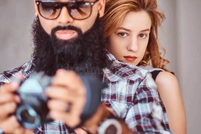 Retrato de un varón barbudo árabe que sostiene una cámara y de su novia hermosa del pelirrojo foto de archivo Retrato de un varón barbudo árabe que sostiene una cámara y de su novia hermosa del pelirrojo foto de archivo
