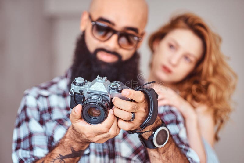 Retrato de un varón barbudo árabe que sostiene una cámara y de su novia hermosa del pelirrojo foto de archivo Retrato de un varón barbudo árabe que sostiene una cámara y de su novia hermosa del pelirrojo foto de archivo