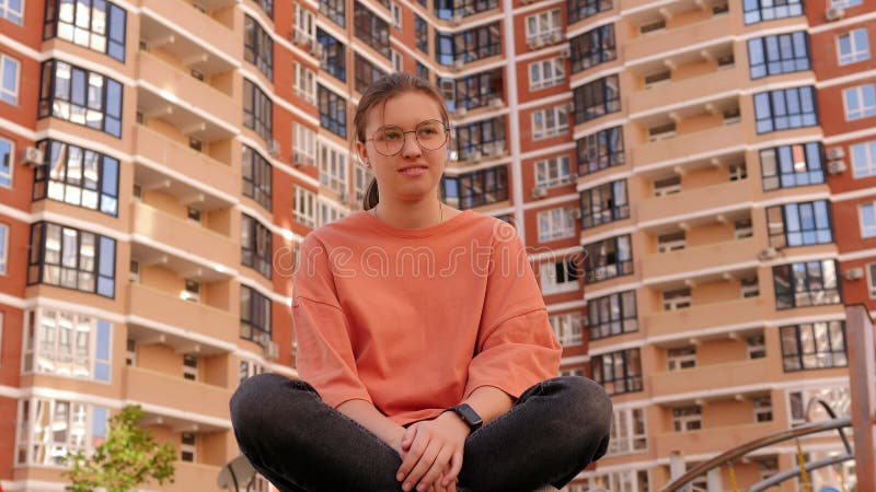 Retrato de una adolescente con gafas en el patio al fondo de un edificio. almacen de video