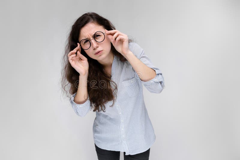 Retrato de una chica joven en vidrios Chica joven hermosa en un fondo gris Una chica joven en una blusa y una oscuridad ligeras fotos de archivo libres de regalías Retrato de una chica joven en vidrios Chica joven hermosa en un fondo gris Una chica joven en una blusa y una oscuridad ligeras fotos de archivo libres de regalías