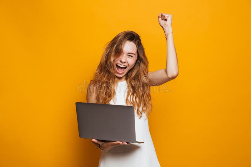 Retrato de una chica joven feliz que sostiene el ordenador portátil