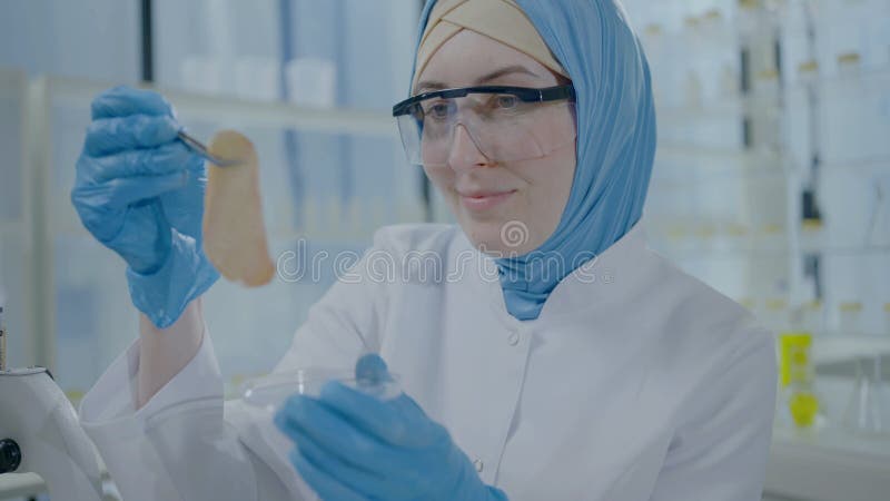 Retrato de una científica musulmana positiva con hijab y abrigo blanco que contiene una muestra de carne artificial con placa de p