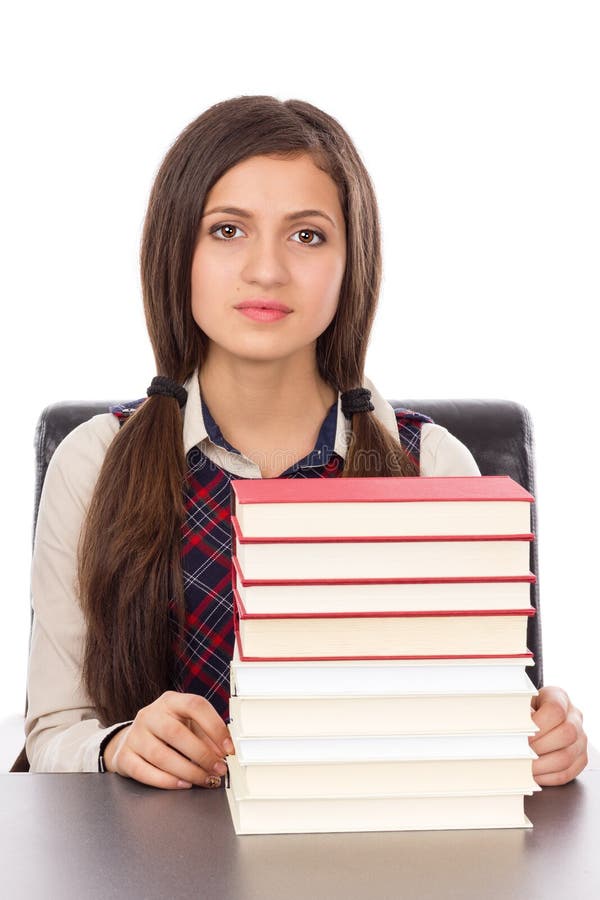 Portrait of a schoolgirl with a stack of books sitting at her desk isolated on white background. Portrait of a schoolgirl with a stack of books sitting at her desk isolated on white background