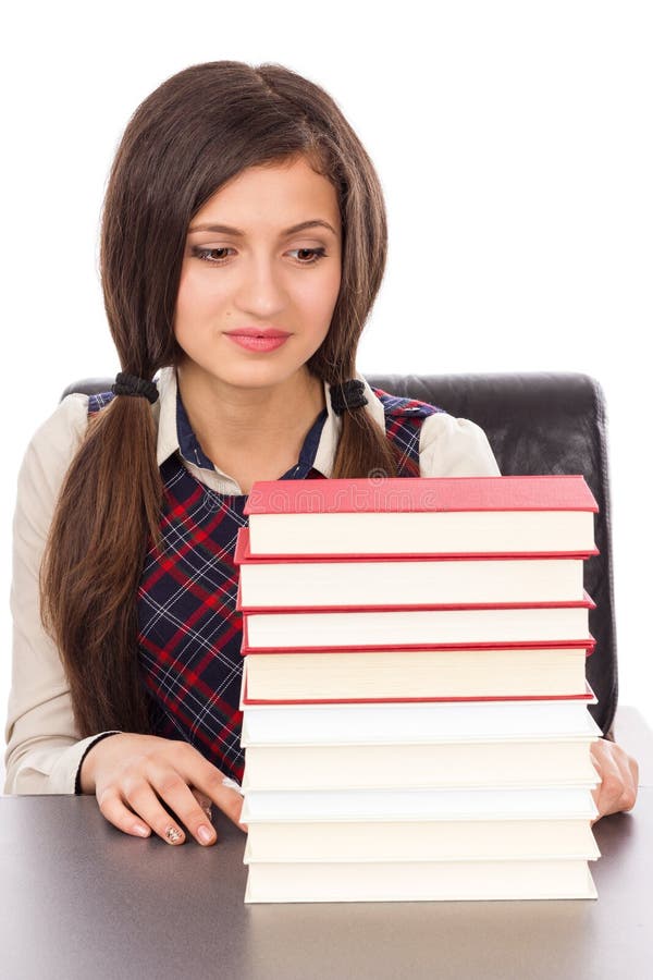 Portrait of a schoolgirl looking to a stack of books isolated on white background. Portrait of a schoolgirl looking to a stack of books isolated on white background