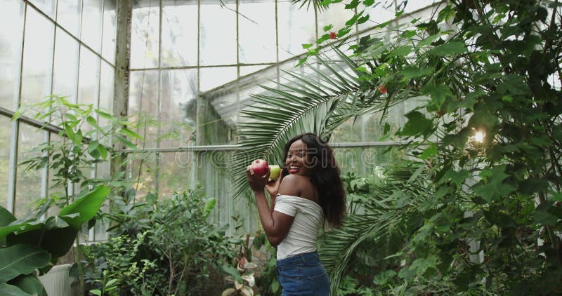 Retrato de una hermosa mujer bailando y cantando en cámara lenta del jardín botánico. atractiva chica negra sosteniendo un almacen de metraje de vídeo