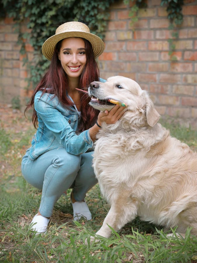 Retrato de una joven artista de 30 años y su perro mascota, el tirador de oro, sentada y sosteniendo pinceles en su imagenes de archivo Retrato de una joven artista de 30 años y su perro mascota, el tirador de oro, sentada y sosteniendo pinceles en su imagenes de archivo