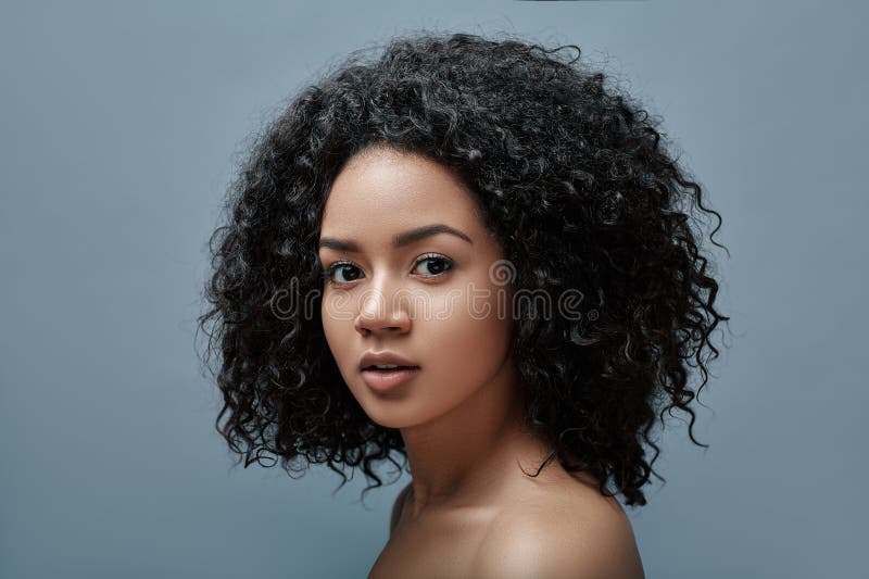 Retrato de una joven con pelo rizado mirando la cámara fotografía de archivo libre de regalías