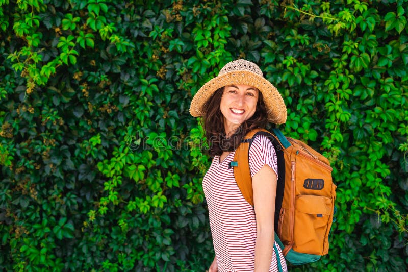 Retrato de una joven con un sombrero y una mochila al fondo de una pared verde. vacaciones de verano imagen de archivo libre de regalías