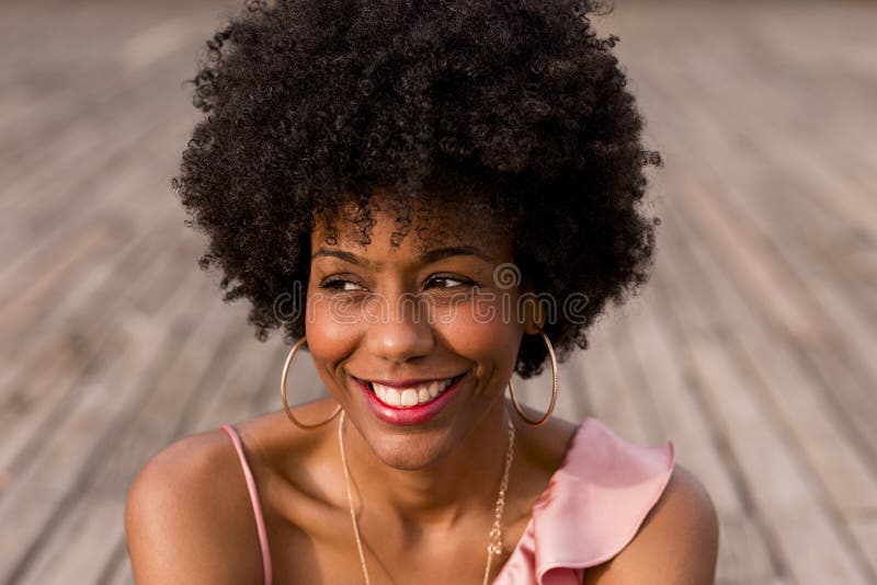 Retrato de una joven feliz afro-americana sentada en el suelo de madera y sonriente Temporada de primavera o verano imágenes de archivo libres de regalías