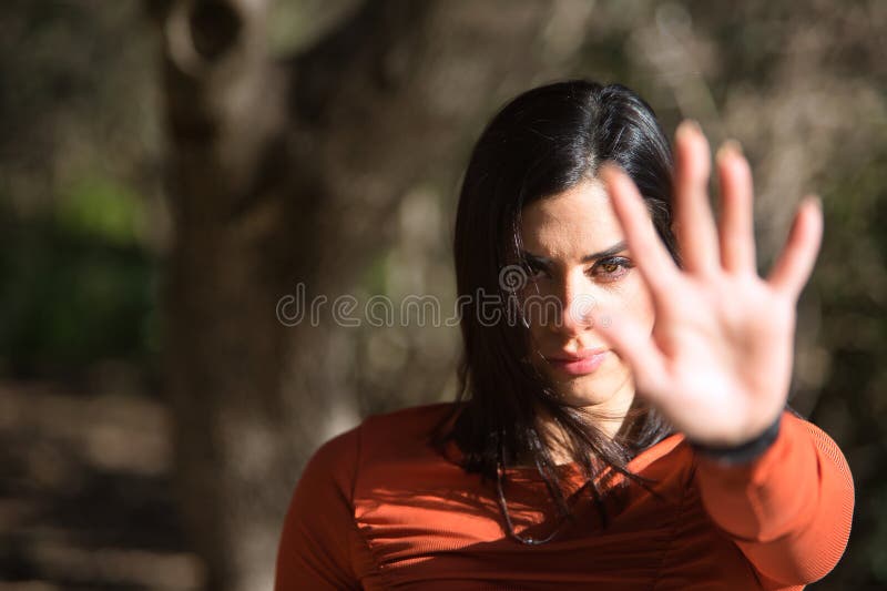 Retrato de una joven hermosa mujer con una camiseta naranja que cubre la cámara con la palma de la mano como signo de rechazo y negación. concepto no rechazo repulsión